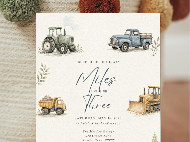 May include: A rectangular invitation card featuring watercolor illustrations of a green tractor, a blue pickup truck, a yellow dump truck, and a yellow bulldozer. The text reads: BEEP BLEEP HOORAY! Miles is turning THREE SATURDAY, MAY 16, 2026 at 2 o'clock in the afternoon The Meadow Garage 218 Clover Lane Austin, Texas 78703.