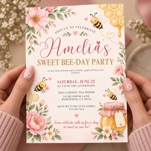 Peut inclure: Une carte d'invitation rectangulaire ornée d'illustrations à l'aquarelle de fleurs roses, de feuilles vertes, de rayons de miel et d'abeilles. Le texte indique : JOIN US TO CELEBRATE Amelia's SWEET BEE-DAY PARTY, avec les détails de l'événement.