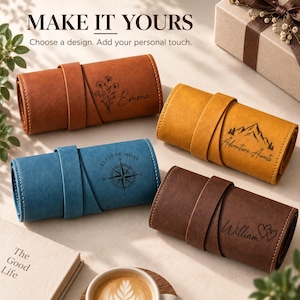 May include: Four cylindrical leather cases in tan, yellow, blue, and dark brown, each featuring a wrap-around strap. The cases are engraved with custom designs including a floral motif with the name Emma, a mountain scene, a compass, and the name William.