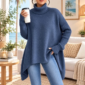 May include: A blue roll-neck jumper with a loose, oversized fit, long sleeves featuring ribbed cuffs, and a high-low hemline. The knit fabric has a soft, heathered texture. The jumper is paired with light blue denim jeans.