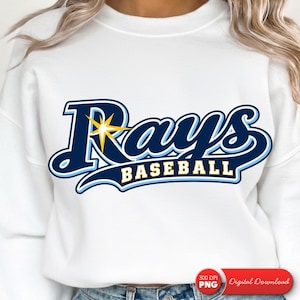 Könnte beinhalten: Ein weißes Sweatshirt mit Rundhalsausschnitt und dem dunkel- sowie hellblauen Rays Baseball-Logo auf der Brust. Die Grafik enthält einen gelben Sternakzent auf dem Buchstaben R und das Wort BASEBALL in gelben Blockbuchstaben.