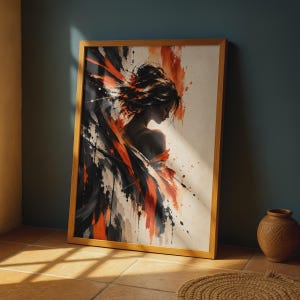 May include: A framed wall art print featuring an abstract painting of a person in profile, rendered in bold black and orange brushstrokes against a cream background. The artwork is enclosed in a light-toned wooden frame, showcasing a dynamic composition.