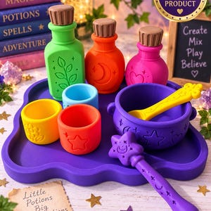 May include: A set of colourful silicone potion-making toys including three bottles with brown stoppers, three small cups, a purple cauldron, and a purple wand with a star tip. The items feature embossed designs like moons, stars, and hearts, arranged on a purple tray.
