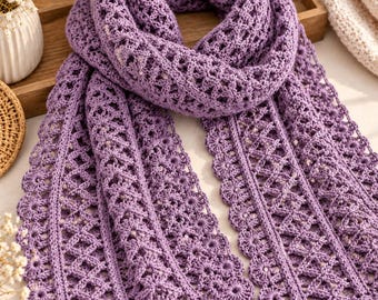 May include: A lavender crochet scarf featuring an intricate openwork pattern with a repeating diamond motif and a scalloped edge. The scarf is crafted from yarn and displays a consistent, detailed texture throughout its entire length.