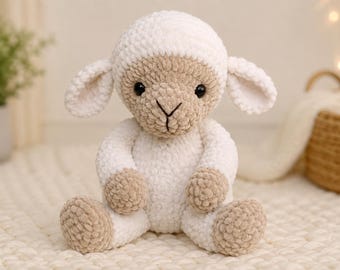May include: A plush stuffed animal in the shape of a lamb, crafted from white and beige yarn. The lamb features a round head, floppy ears, black plastic eyes, and a stitched nose. Its body is seated with beige paws and feet.