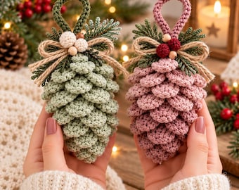May include: Two crocheted pinecone ornaments, one in sage green and one in dusty rose. Each features a top loop, a jute twine bow, small wooden beads, and green yarn sprigs. The textured, layered yarn construction mimics the appearance of natural pinecones.