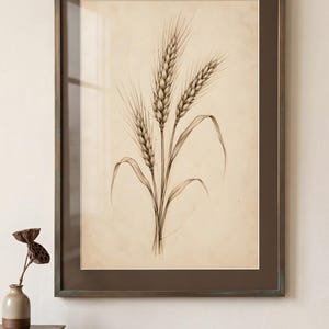 以下が含まれることがあります： クリーム色の背景に3本の小麦の穂を描いた、詳細な木炭画風のフレーム入りアートプリント。作品はダークブラウンのフレームとマッチしたマットで囲まれており、繊細な線と植物の質感が表現されています。
