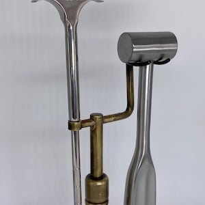 May include: Three metal tools, including one with "FREEMAN" stamped on the top. The tools are silver and brass in color. One tool has a hammer-like head, another has a curved handle, and the third has a T-shaped head.