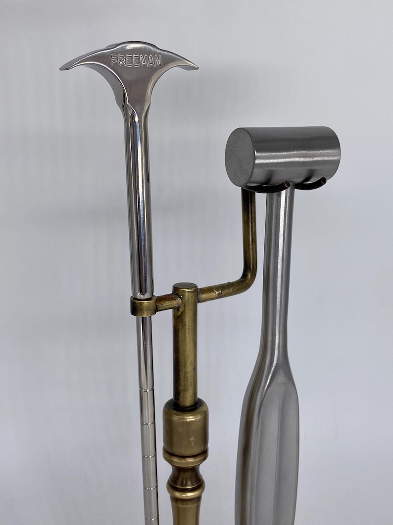 May include: Three metal tools, including one with "FREEMAN" stamped on the top. The tools are silver and brass in color. One tool has a hammer-like head, another has a curved handle, and the third has a T-shaped head.
