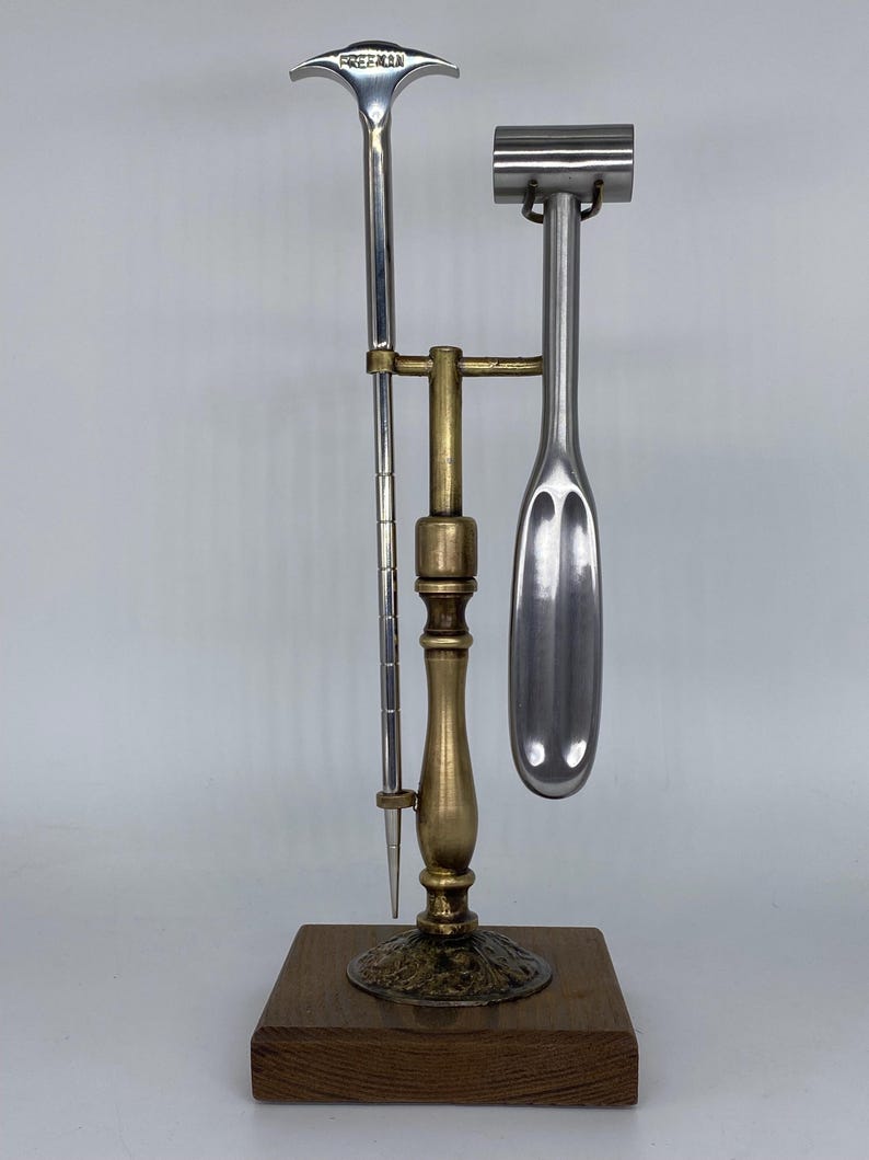 May include: A vintage bar tool set with a wooden base. The set includes a metal ice pick, a muddler, and a bottle opener. The bottle opener has the word "FREEMAN" engraved on it. The tools are made of silver and brass.