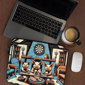 Peut inclure: Une housse d'ordinateur portable illustrée de trois cochons attablés dans une taverne, avec des chopes de bière, des plats, une cible de fléchettes sur un mur en briques bleues et des meubles en bois, posée près d'un ordinateur, souris et café.