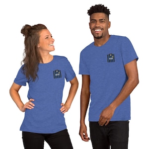 May include: A heather blue short-sleeve t-shirt featuring a small graphic on the left chest. The graphic depicts a black and blue vertical striped soccer jersey with the word INTER printed in white text across the center of the chest area.