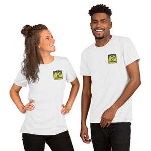 May include: Two white short-sleeved t-shirts featuring a small, square graphic on the left chest. The graphic depicts a yellow football shirt with black trim and the text DORTMUND printed in black, along with a small circular emblem.