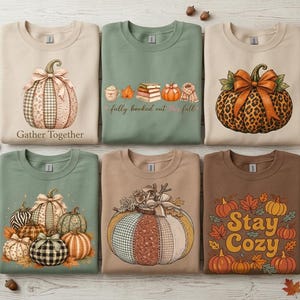 May include: Six crewneck sweatshirts in beige, sage green, and brown featuring autumn-themed graphics. Designs include pumpkins with plaid, leopard, and floral patterns, a stack of books with the text fully booked out full, and fall leaves.