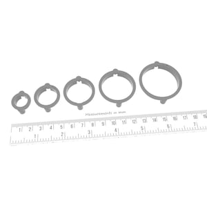 May include: Four gray plastic rings of different sizes, measured in millimeters, on a white surface.
