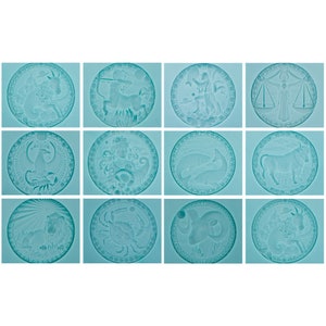 Op de afbeelding: Twaalf ronde, blauw getinte glazen borden met gegraveerde afbeeldingen van de dierenriemtekens. Elk bord heeft een ander dierenriemteken, waaronder Ram, Stier, Tweelingen, Kreeft, Leeuw, Maagd, Weegschaal, Schorpioen, Boogschutter, Steenbok, Waterman en Vissen.