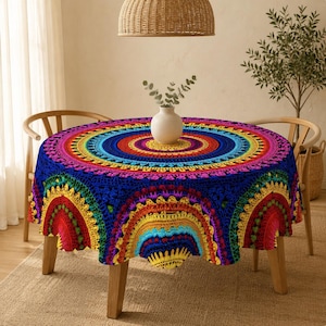 Op de afbeelding: Een rond tafelkleed met een levendig, veelkleurig mandalapatroon met concentrische cirkels in tinten rood, oranje, geel, groen, blauw en paars. Het ontwerp bevat ingewikkelde, herhalende geometrische en bloemachtige motieven.