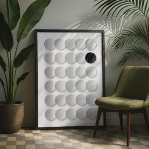 May include: A framed rectangular wall art piece featuring a grid of light gray circles on a white background, with one single solid black circle positioned in the fourth row of the grid. The artwork is enclosed in a thin black frame.