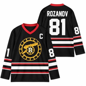 May include: A black long-sleeve hockey jersey with a red V-neck collar. The front features a yellow circular logo with a cannon and the letter R, plus a white C. The back displays the name ROZANOV and number 81 in white, with red and white stripes.