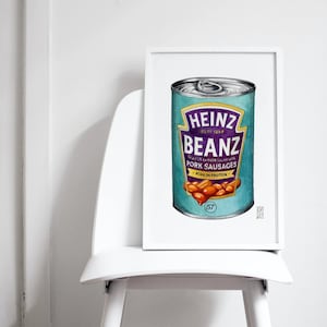 May include: A framed illustration of a Heinz Beanz can with a blue background and purple text. The can is filled with brown beans and the text reads "Heinz Beanz Baked Beans with Pork Sausages High in Protein".