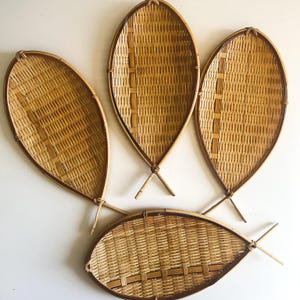 May include: Four light brown woven bamboo trays shaped like fish, each featuring a distinct lattice pattern and a reinforced rim. The trays are arranged in a cluster, with three positioned vertically and one placed horizontally at the bottom.