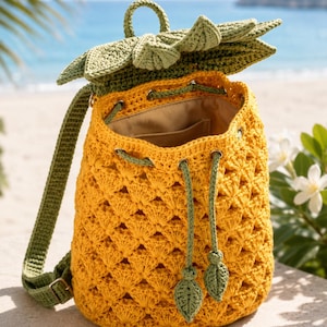 May include: A crochet backpack shaped like a pineapple with a yellow textured body, a green leafy top flap, and green drawstring cords with leaf-shaped ends. The bag features adjustable green shoulder straps and a light-colored interior lining.