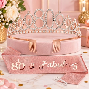 May include: A rose gold tiara featuring the number 80 encrusted with clear rhinestones and two attached hair combs, paired with a matching rose gold glitter sash printed with the text 80 & Fabulous and a small safety pin for closure.