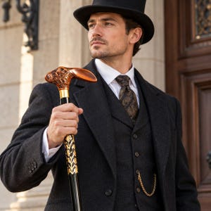 May include: A black top hat and a dark charcoal three-piece suit with a white collared shirt and a patterned tie. A walking cane features a carved wooden rabbit head handle, a gold-colored collar, and a black shaft with gold floral accents.