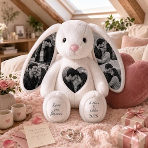 Puede incluir: Un conejo de peluche blanco con impresiones fotográficas en blanco y negro en las orejas y un parche en forma de corazón en el pecho. El pie izquierdo tiene el texto Love you forever y el derecho Arthur & Chloe 2026 en letra negra.