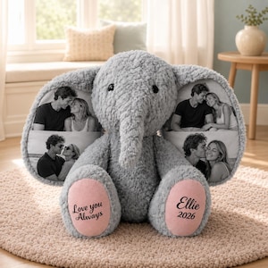May include: A grey plush elephant toy with large ears featuring printed black and white photographs of couples. The elephant has pink foot pads with the text "Love you Always" on the left foot and "Ellie 2026" on the right foot.