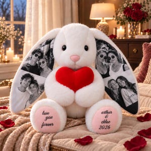 May include: A white plush rabbit holding a red heart, featuring black and white photo prints on its long ears. The rabbit has pink paw pads with the text 'love you forever' on the left and 'arthur & chloe 2026' on the right.