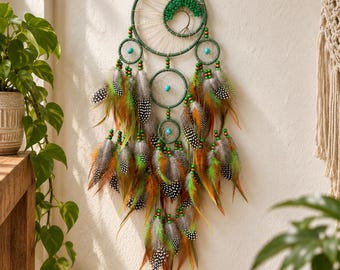 May include: A wall-hanging dream catcher featuring a large green circular frame with a tree-like wire design and green beads. It includes smaller circular frames, turquoise accents, and a cascade of brown, green, and black-spotted feathers.