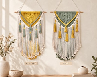May include: Two macrame wall hangings suspended from wooden dowels. The left piece features mustard yellow and cream cord with sage green tassels. The right piece features sage green and cream cord with mustard yellow tassels. Both have geometric patterns.