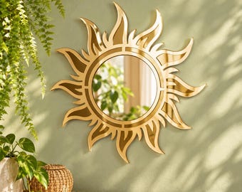 May include: A circular wall mirror featuring a gold-toned frame shaped like stylized sun rays. The central glass is round, surrounded by a decorative border of pointed, flame-like metallic segments that extend outward in a sunburst pattern.