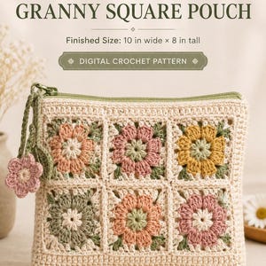 May include: A rectangular crochet pouch featuring six granny squares with floral motifs in muted pink, yellow, and green on a cream background. The pouch has a green zipper with a small flower charm and measures 10 inches wide by 8 inches tall.