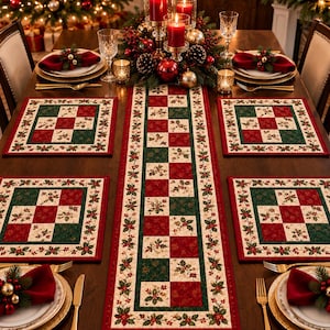 May include: A rectangular table runner and four matching square placemats featuring a patchwork design of red, dark green, and cream squares with holly leaf and berry patterns. The fabric items have a red border and quilted texture.