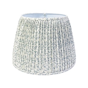 May include: A white lampshade with a blue floral pattern. The lampshade is pleated and has a white lining.