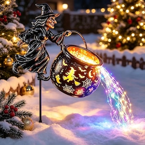 May include: A black metal garden stake featuring a witch figure holding a cauldron. The cauldron is decorated with cutouts of witches, ghosts, and spiderwebs, and it emits a cascade of multicolored LED fairy lights onto the snowy ground.