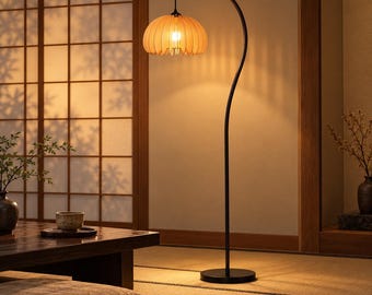 Può includere: Una lampada da terra con un sottile supporto in metallo nero curvo e una base circolare. Il corpo illuminante presenta un paralume in legno chiaro a forma di zucca con listelli verticali che emettono una luce calda e soffusa.