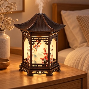 Peut inclure: Un diffuseur d'huiles essentielles en bois foncé en forme de pagode traditionnelle avec une base et un toit hexagonaux. Le panneau cylindrique central présente une illustration rétroéclairée de cerisiers en fleurs et de montagnes.
