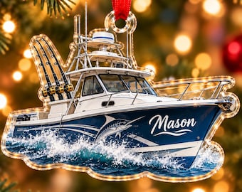 Op de afbeelding: Een platte, uitgesneden kerstornament in de vorm van een sportvissersboot met een witte cabine, blauwe romp en drie hengels. De naam Mason staat in witte schrijfletters op de zijkant, samen met een afbeelding van een marlijn en wit water.