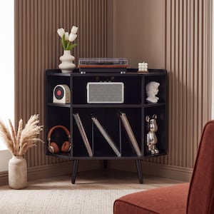 May include: A black corner media console with tapered legs, featuring three top shelves and three angled lower compartments for vinyl records. The unit holds a turntable, a white speaker, a small bust, and a candle, with a vase of tulips on top.