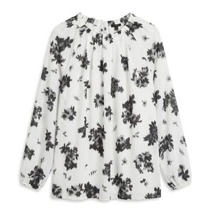 May include: A long-sleeved blouse in white featuring a black floral print. The garment has a round neckline with subtle pleating details, a button closure at the back of the neck, and elasticized cuffs at the ends of the sleeves.
