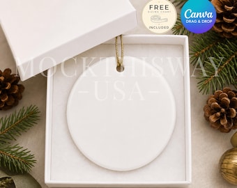 Puede incluir: Un adorno de cerámica blanco de forma circular con un cordón dorado para colgar, presentado dentro de una caja de regalo cuadrada blanca abierta. El adorno es liso y está en blanco, con un orificio central para el cordón. La caja está sobre un fondo festivo.