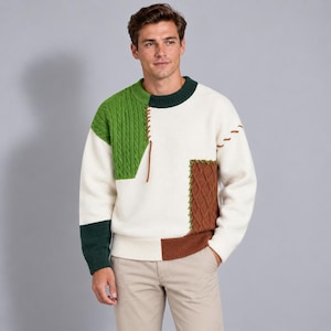 Pode incluir: Uma camisola de manga comprida com gola redonda e um design de blocos de cor em creme, verde floresta e castanho. A peça inclui um painel de malha trançada verde na parte superior direita, um painel texturizado castanho em baixo à esquerda e uma gola canelada verde escura.