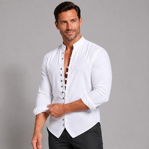 May include: A crisp white long-sleeve shirt featuring a mandarin collar and a vertical row of small dark buttons down the front. The shirt has a tailored fit with sleeves rolled up to the forearms, paired with dark charcoal trousers.