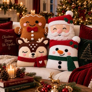 May include: Four crochet cushions featuring festive characters: a brown gingerbread person with a red bow tie, a Santa Claus with a white beard and red hat, a brown deer with a red scarf, and a white snowman with a green scarf and orange nose.