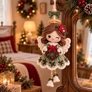 May include: A crocheted angel ornament featuring brown yarn hair, a green dress with red berry accents, white wings, and a yellow halo. The figure holds a small green wreath with a red bow and has two white bell-shaped ornaments hanging below.