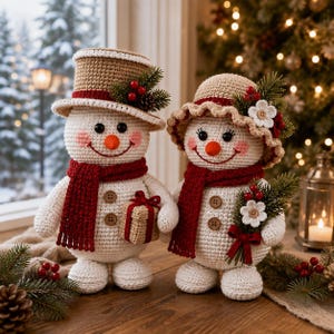 May include: Two crocheted snowmen figures with white bodies, orange noses, and pink cheeks. One wears a tan top hat with pine and red berries, the other a tan sun hat with white flowers and berries. Both wear red scarves and brown buttons.