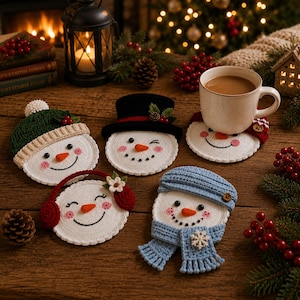 Pode incluir: Cinco bases para copos em crochê com formato de boneco de neve, com rostos brancos, narizes de cenoura laranja, olhos pretos e bochechas rosadas. Cada boneco usa um acessório diferente: um gorro verde, uma cartola preta ou um boné azul.